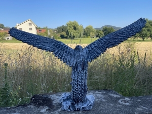 betonfarbene adlerfigur mit ausgebreiteten fluegeln von vorne