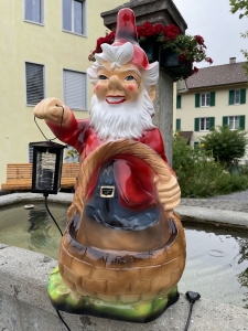 Grosser Gartenzwerg mit Pflanzkorb, roter Muetze und schwarzer Laterne.