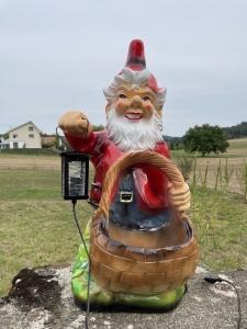 Frontansicht des beleuchteten Gartenzwergs mit Korb als Pflanzgefaess.