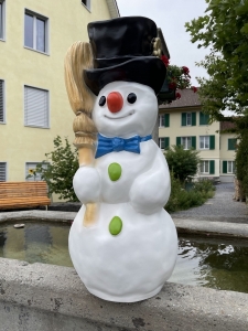 Schneemann mit schwarzem Zylinder als Outdoor-Weihnachtsdeko.