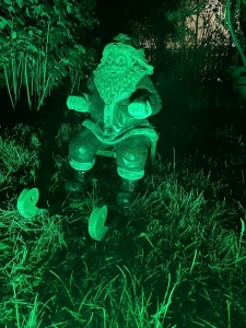 Weihnachtsmann mit Schlitten in gruener Beleuchtung.